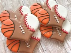 four decorated cookies in the shape of baseballs and balls on a wooden table top