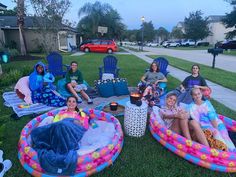 a group of people sitting on inflatable chairs outside at dusk with drinks and snacks