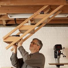 a man is holding up a ladder to the ceiling