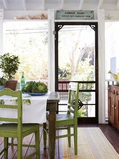 a dining room table with green chairs and an open door