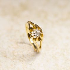 a yellow gold ring with a diamond in the center on a white surface, close up