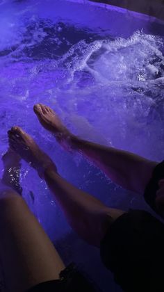 two people are sitting in a hot tub with their feet on the edge and water around them