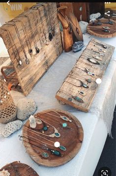 an assortment of jewelry is displayed on a table with white linens and wooden crates