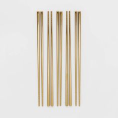 four gold colored chopsticks on a white surface