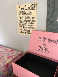 a pink box with the words to be opened in 2013 written on it next to a bed