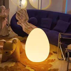 an egg shaped lamp sitting on top of a floor next to a couch and table