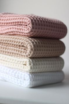 three folded towels stacked on top of each other in pastel colors, with one folded over the edge