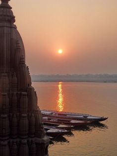 the sun is setting over some water with boats in the foreground and another boat on the other side