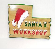 a wooden sign that says santa's workshop with a santa hat on the top