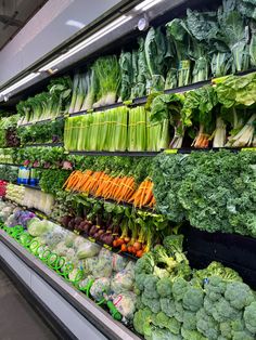 an assortment of vegetables are on display in a grocery store, including broccoli, lettuce and carrots