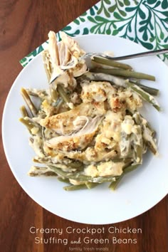 creamy crockpot chicken stuffing and green beans on a white plate with a fork