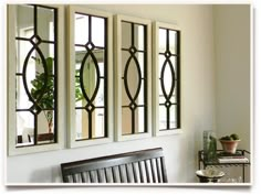 three windows in a room with a bench and potted plant