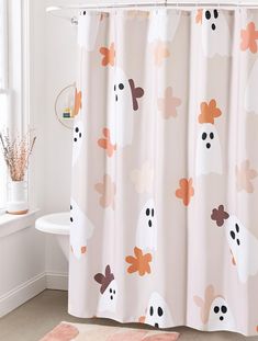 a bathroom with a shower curtain that has ghost and pumpkins on it, along with a pink rug