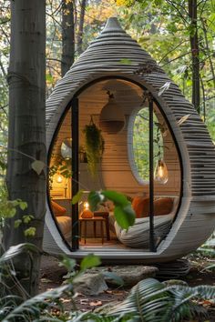 a small round house in the woods surrounded by greenery and trees, with an outdoor seating area