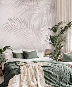 a bedroom with palm leaves on the wall and green bed linens in front of it