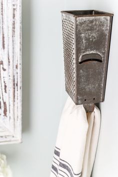 a towel holder is hanging on the wall next to a mirror and vase with flowers in it