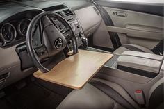 the interior of a car with a wooden table on it's center console and steering wheel