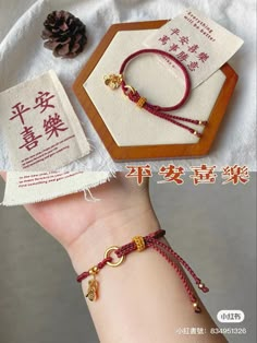 two bracelets with charms on the wrist, one is red and one is gold