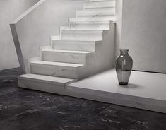 a vase sitting on top of a table next to a stair case in a room