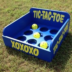 a blue tic - tac - toe game sitting in the grass with yellow balls