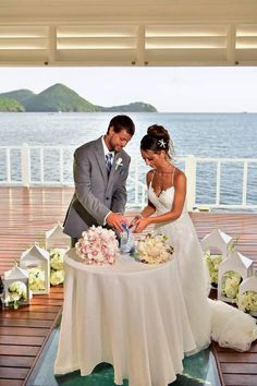 a bride and groom cutting their wedding cake on the deck of a boat in the ocean