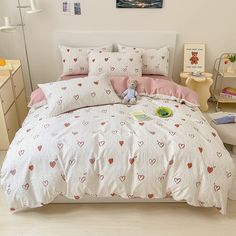 a bed with hearts on it in a bedroom next to a dresser and desks