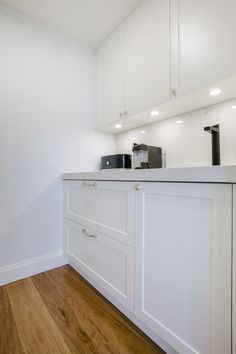 a kitchen with white cabinets and wood floors