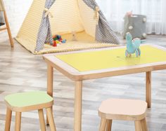 a child's table and two stools in a room with toys on the floor