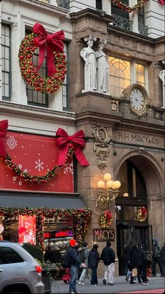 people are walking down the street in front of stores decorated with christmas decorations and wreaths