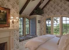 a large bed sitting under two windows in a bedroom next to a fireplace and window sill