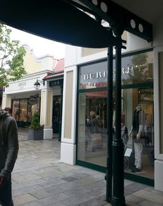 a man is walking down the sidewalk in front of a buurd and store