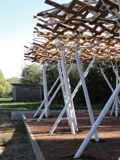 several white wooden structures in the middle of a dirt area with grass and trees behind them