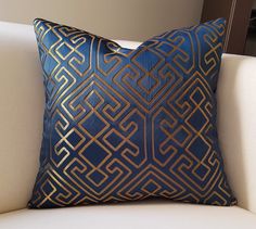 a blue and gold pillow sitting on top of a white couch