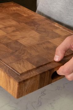 a person is holding onto a cutting board