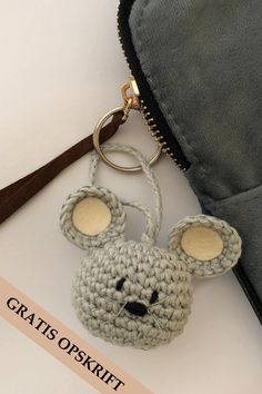 a crocheted mouse keychain hanging from a zippered pouch on a white surface