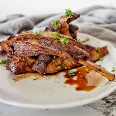 a white plate topped with ribs covered in sauce