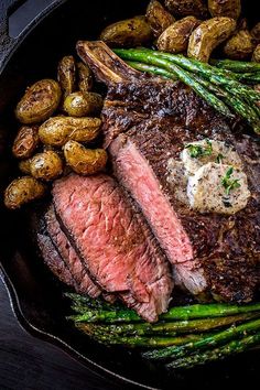 steak, potatoes and asparagus in a cast iron skillet