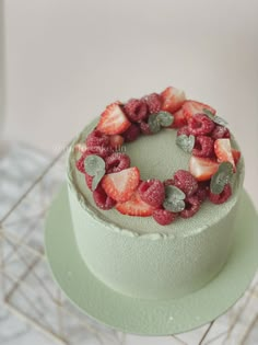 a green cake with strawberries and leaves on top