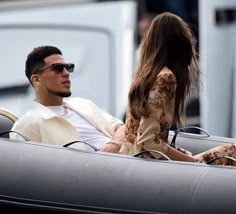 a man and woman are riding in an old convertible car with the driver looking back