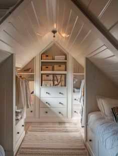 an attic bedroom with white cabinets and drawers