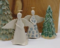 three ceramic figurines are sitting next to each other in front of a piece of wood