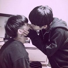 two young men kissing each other in front of a piano