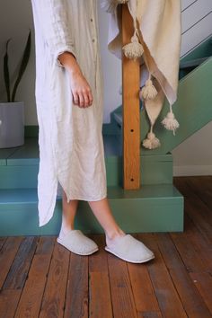 a woman in white slippers standing next to a wooden cross on the steps with a towel draped over her head