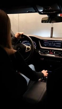 a woman driving a car in the dark with her hands on the steering wheel and dashboard