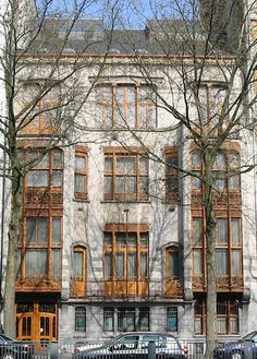 an old building with many windows and balconies on the top floor is surrounded by parked cars