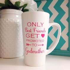 two coffee mugs sitting next to each other on a table with flowers in the background