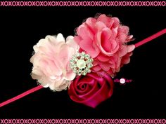 two pink flowers are sitting on top of a red headband with beaded accents