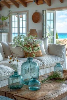 three vases with flowers are sitting on a coffee table in front of a couch