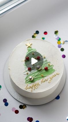 a white cake with a green christmas tree on it and confetti around it