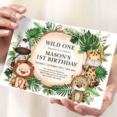 a person holding up a card with animals on it and the words wild one, mason's 1st birthday